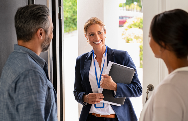 A professional woman greeting clients at an office entrance.