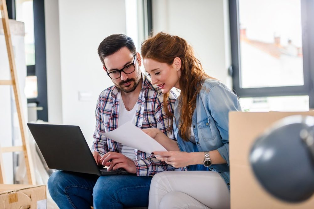 Couple reviewing documents together at home with a laptop.