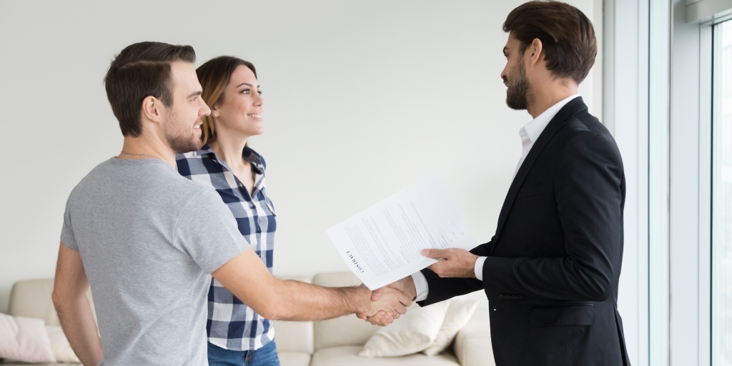 Couple shaking hands with a real estate agent after signing documents.