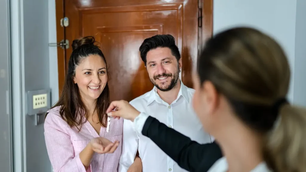 Couple receiving keys from a real estate agent.