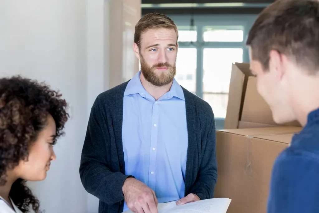 Man with beard discussing paperwork in an office setting.